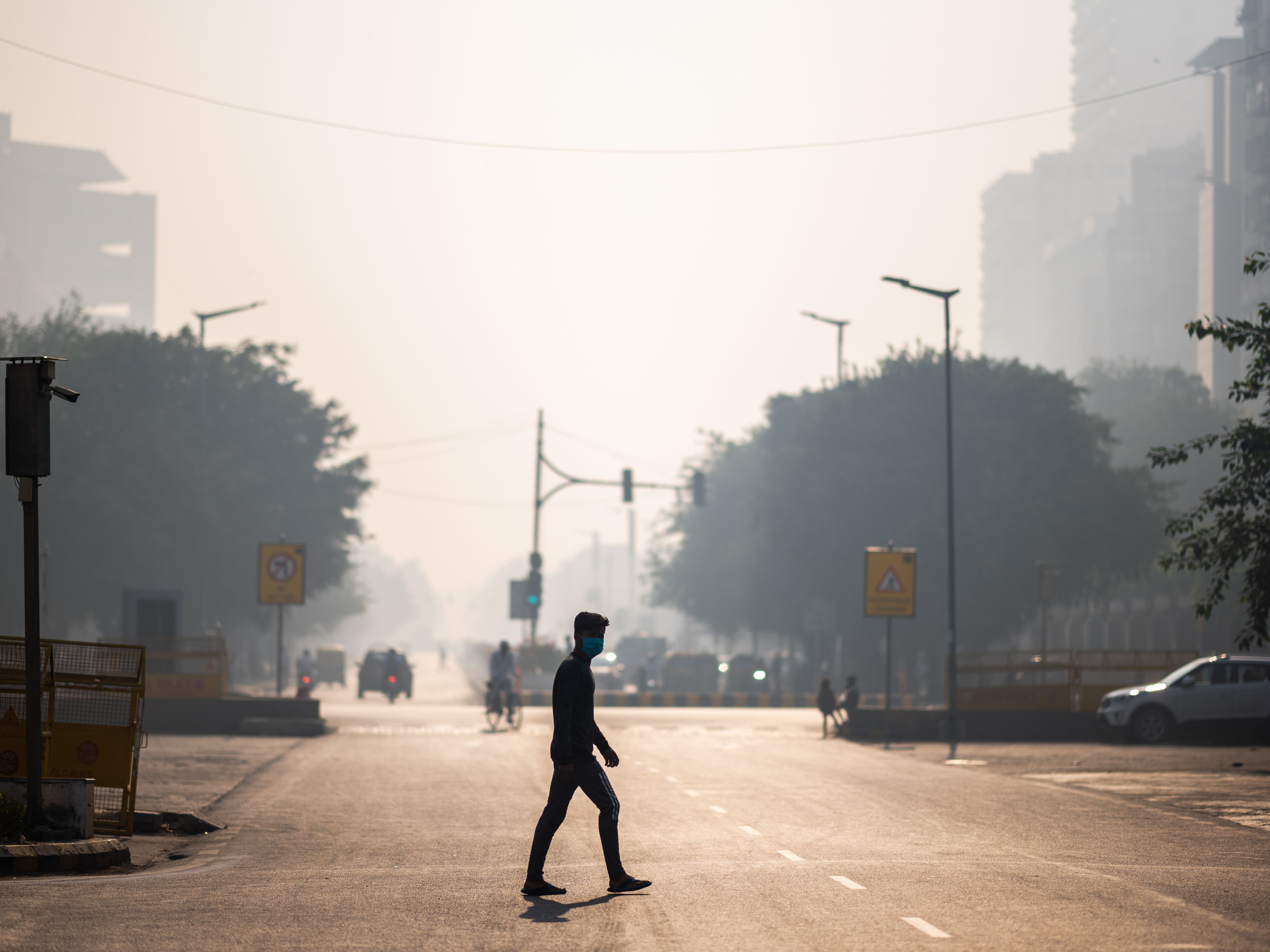 A man wearing a facemask crosses a street amid smoggy condition in New Delhi in October