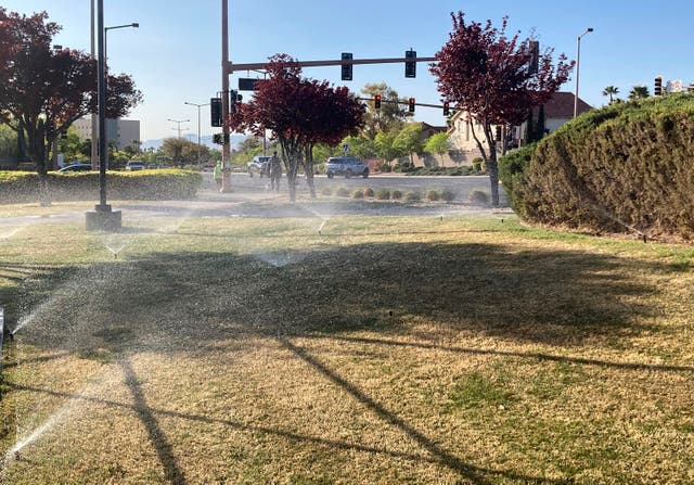 <p>Sprinklers water grass near a street corner on 9 April, 2021, in the Summerlin neighborhood of Las Vegas</p>