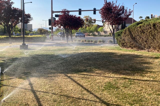 <p>Sprinklers water grass near a street corner on 9 April, 2021, in the Summerlin neighborhood of Las Vegas</p>