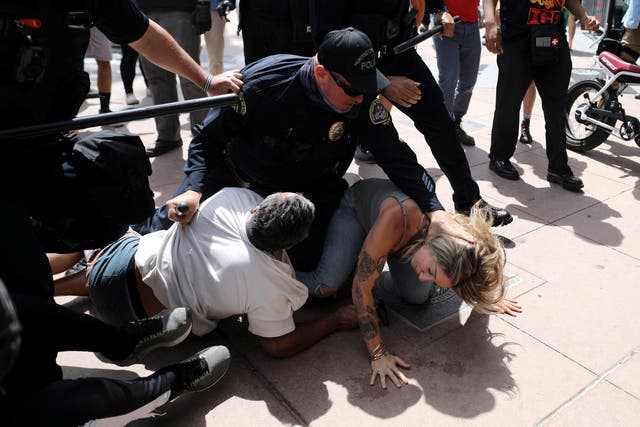 <p>A police officer pins a woman down during confrontations with protesters in Huntington Beach</p>