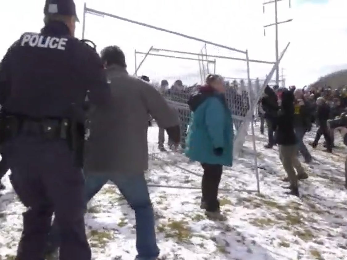 <p>Police attempt to put fences back up taken down by protesters in Edmonton, Alberta, Sunday 11 April 2021</p>