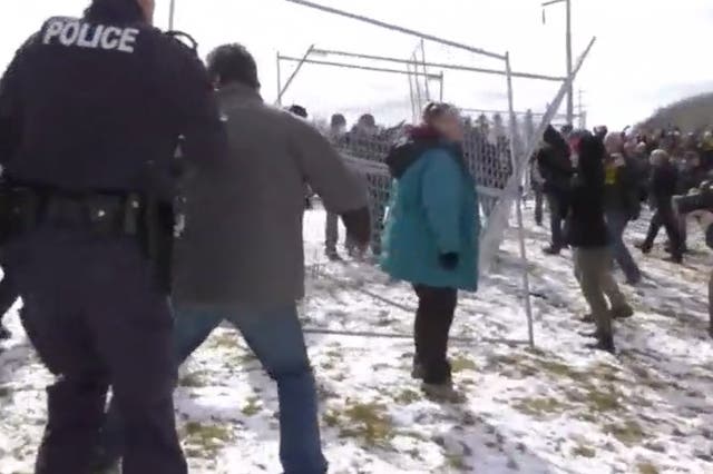 <p>Police attempt to put fences back up taken down by protesters in Edmonton, Alberta, Sunday 11 April 2021</p>