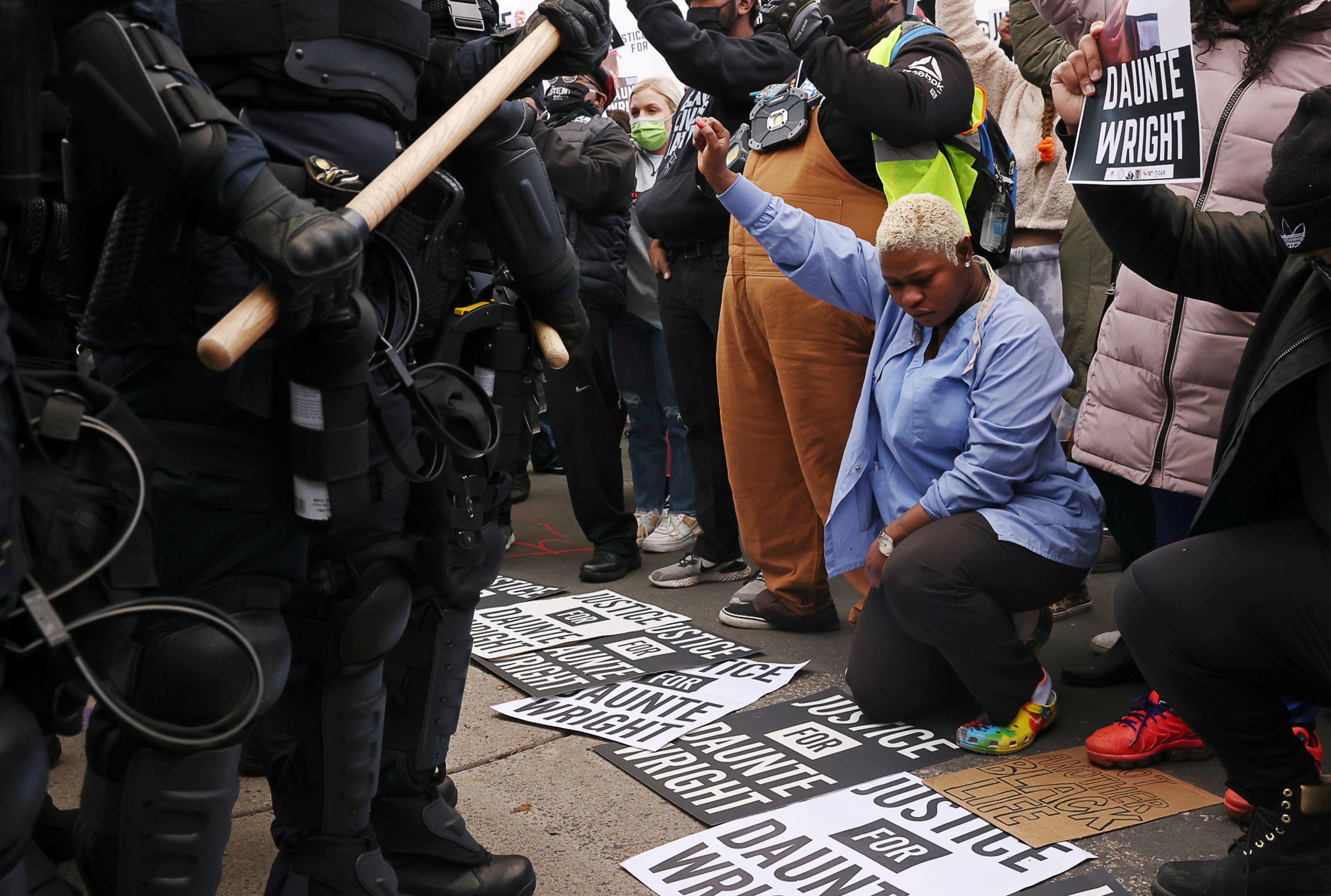 Evelyn Jarbah (in blue) kneels as protesters take a moment of silence during a rally outside Brooklyn Center Police Department, a day after Daunte Wright was shot and killed by a police officer, in Brooklyn Center, Minnesota