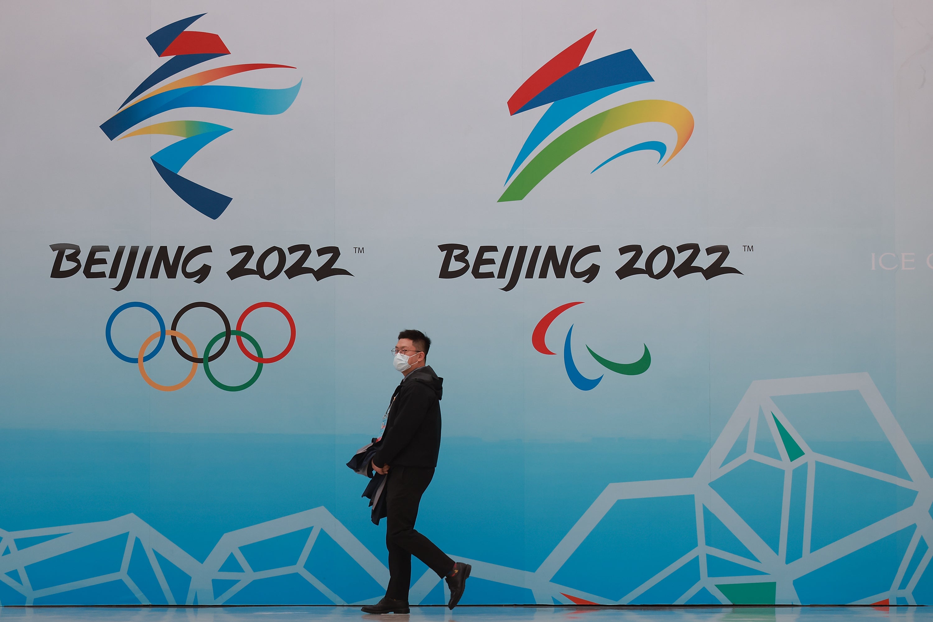 A man walks in front of the logos of the 2022 Beijing Winter Olympics at National Aquatics Centre on 9 April 2021 in Beijing