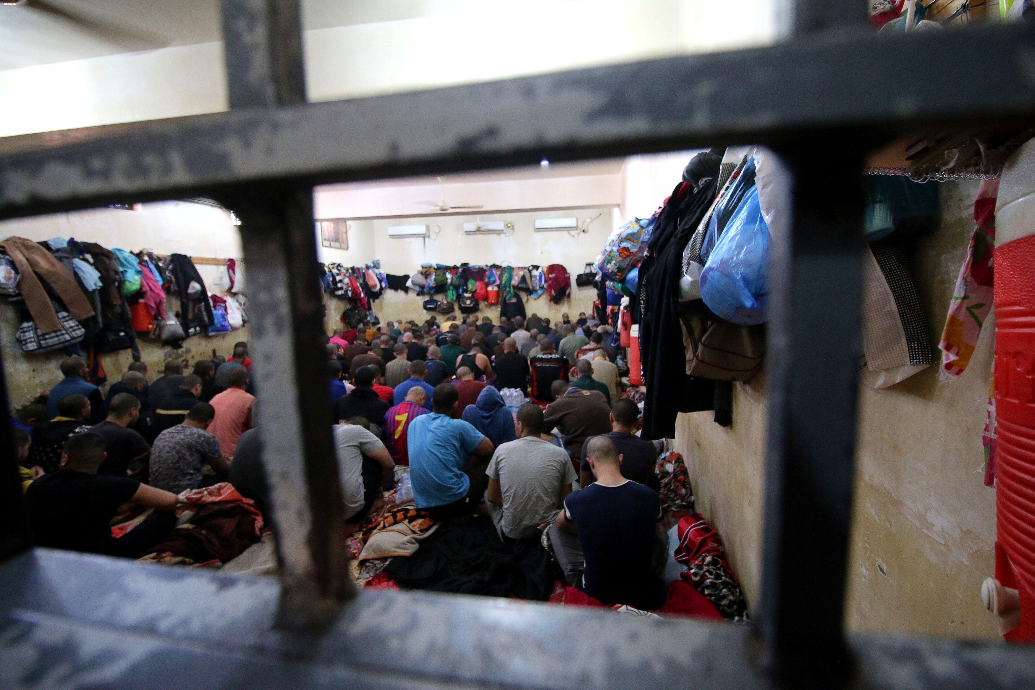 Iraqi suspects who were arrested for drug-related crimes sit on the floor in a cell inside a police station in Basra in 2019