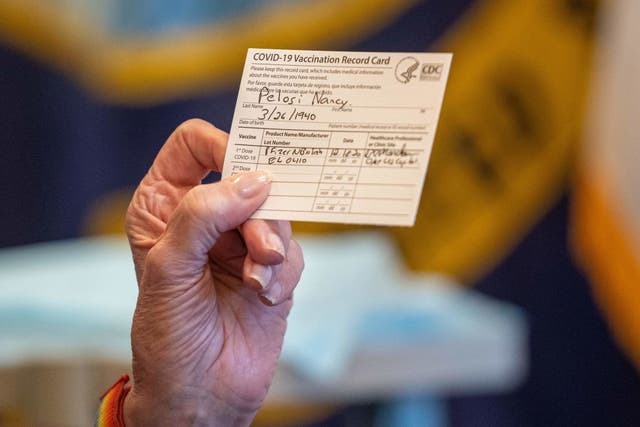 Speaker of the House Nancy Pelosi holds up a Vaccination Record Card after receiving a Covid-19 vaccine shot 