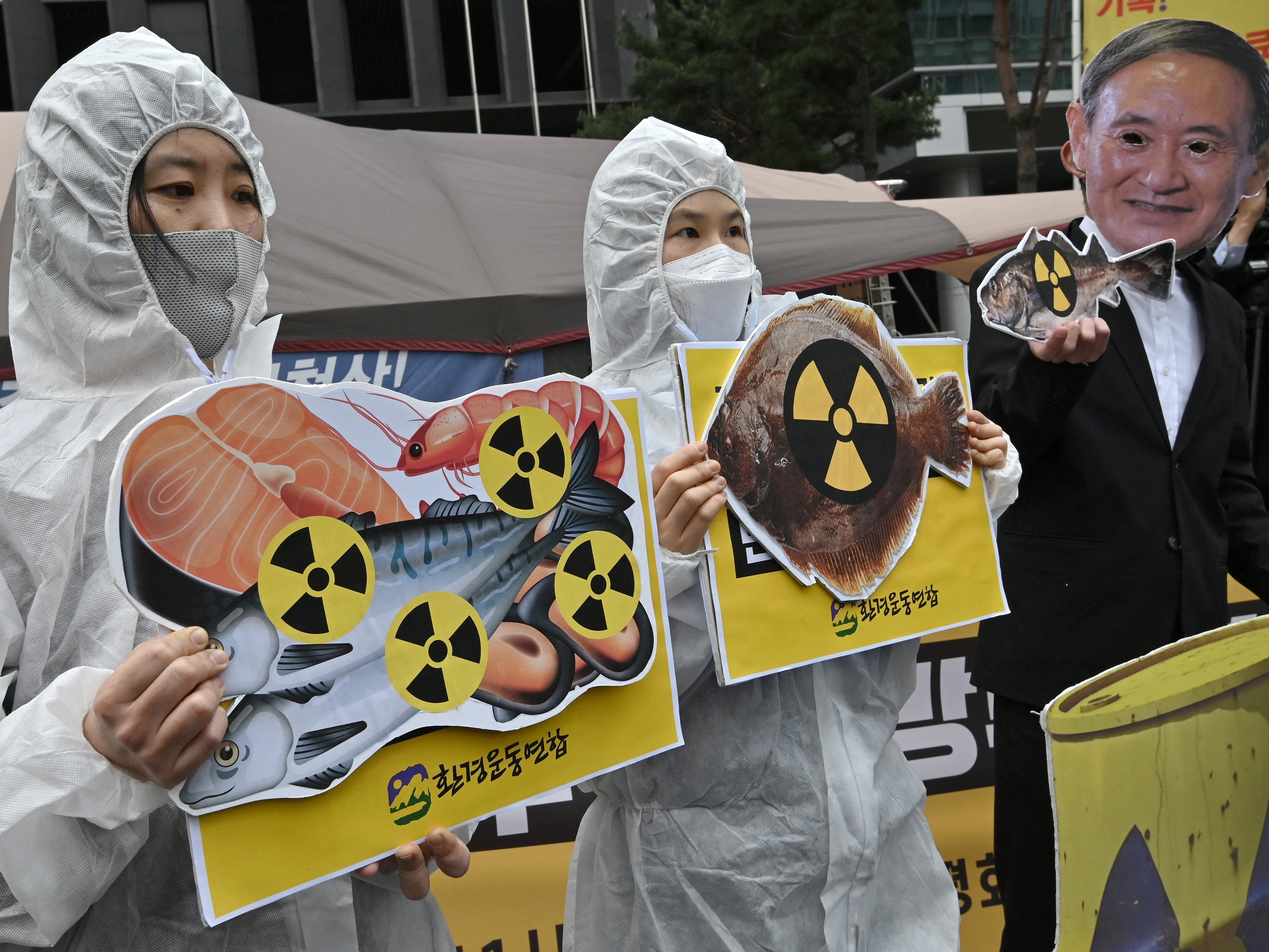 South Korean environmental activists protest outside the Japanese embassy at the decision, one wearing a mask of Japan’s prime minister Yoshihide Suga