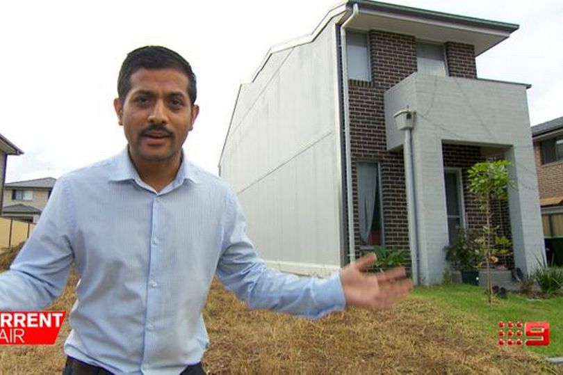 Bishnu Aryal gestures in front of ‘half a house' he claims the building company did not inform him about