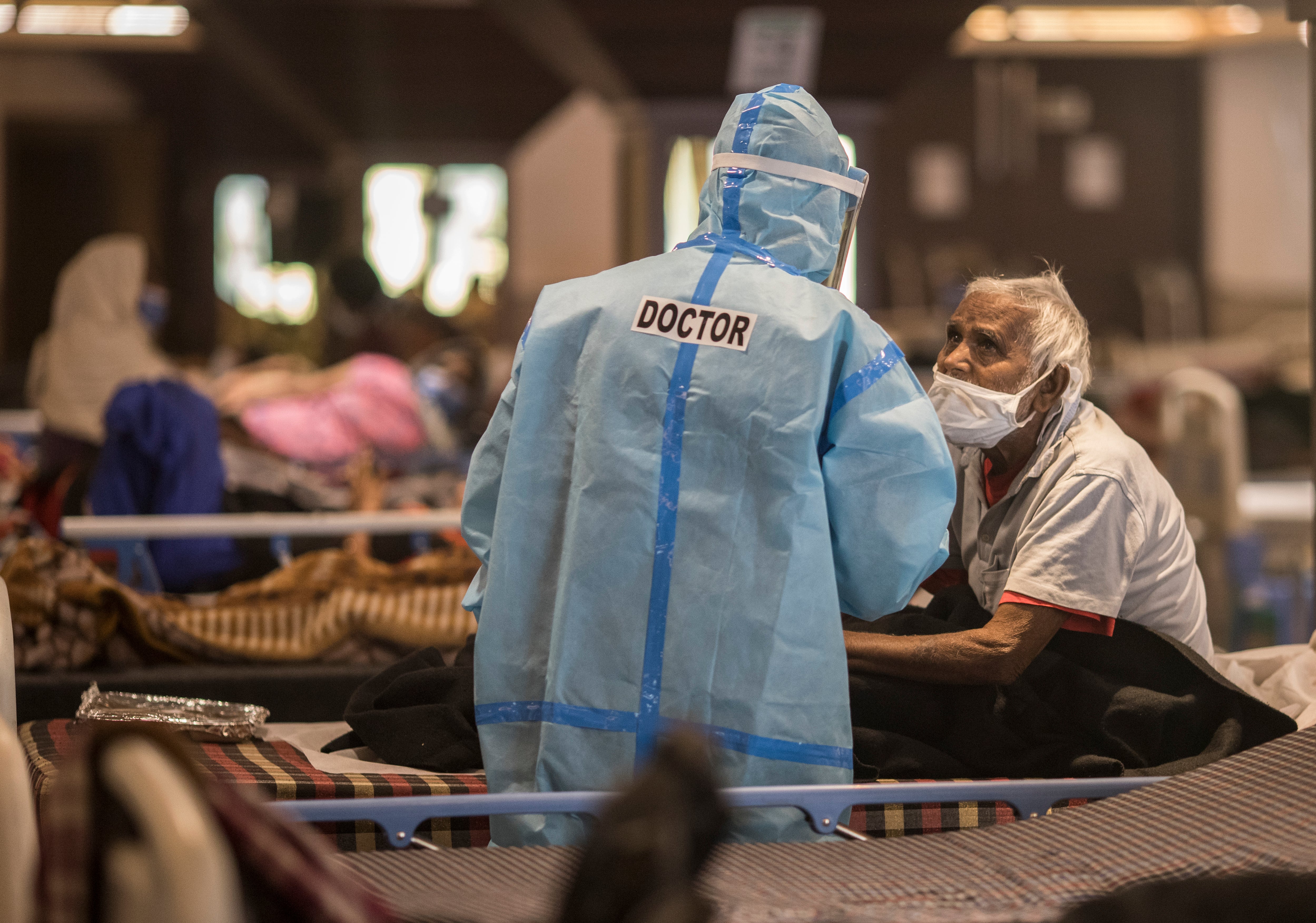 A doctor is seen talking to a patient who was tested positive and was in quarantine at a quarantine centre for Covid-19 coronavirus infected patients at a banquet hall that was converted into an isolation centre to handle the rising cases of infection on 15 April in New Delhi