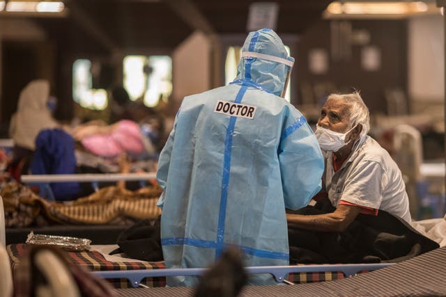<p>A doctor is seen talking to a patient who was tested positive and was in quarantine at a quarantine centre for Covid-19 coronavirus infected patients at a banquet hall that was converted into an isolation centre to handle the rising cases of infection on 15 April in New Delhi</p>