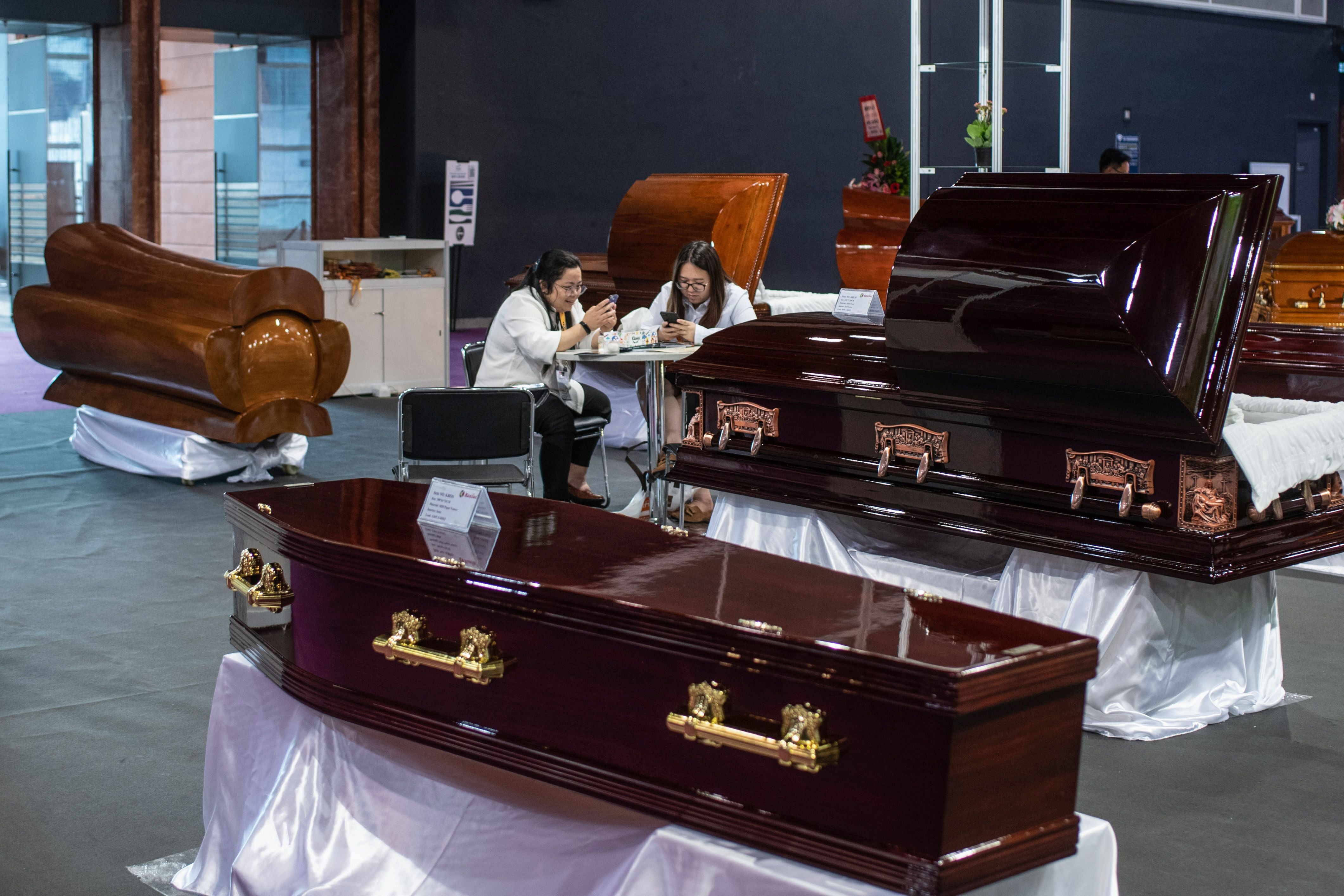Representative: Exhibitors use their mobile phones displaying caskets during the Asia Funeral and Cemetery Expo in Hong Kong on 14 May 2019