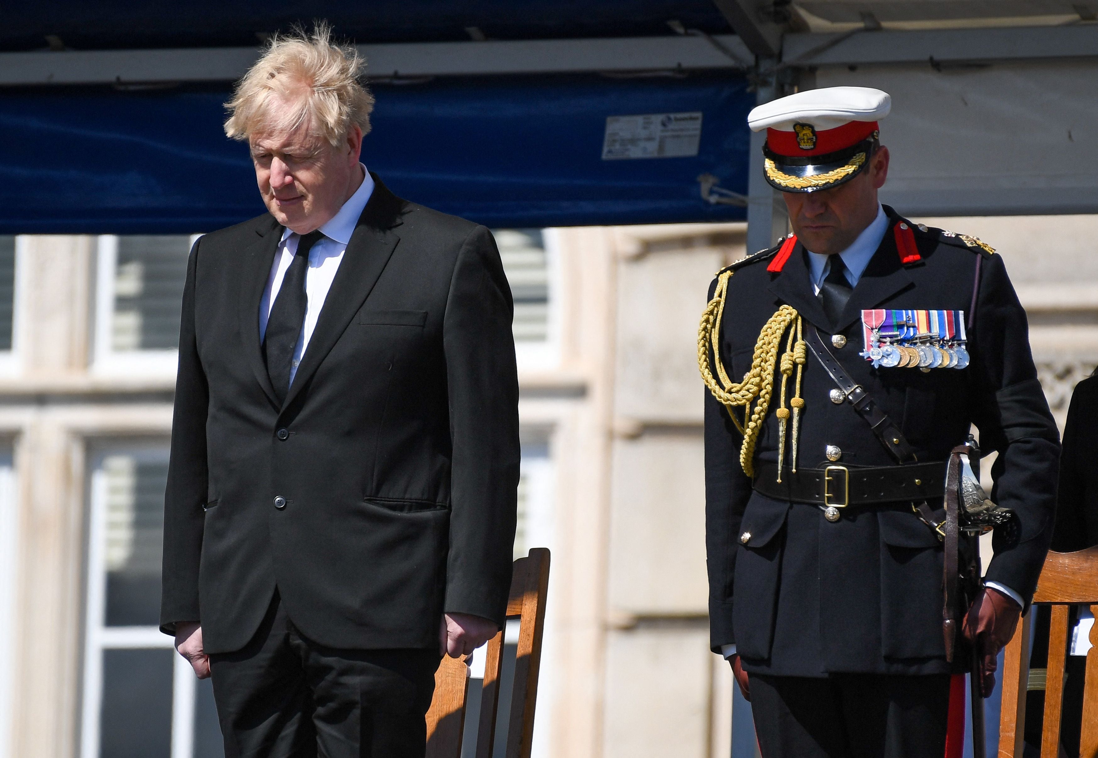 Boris Johnson (L) observes a minutes s silence during a Passing-out parade at Britannia Royal Naval College