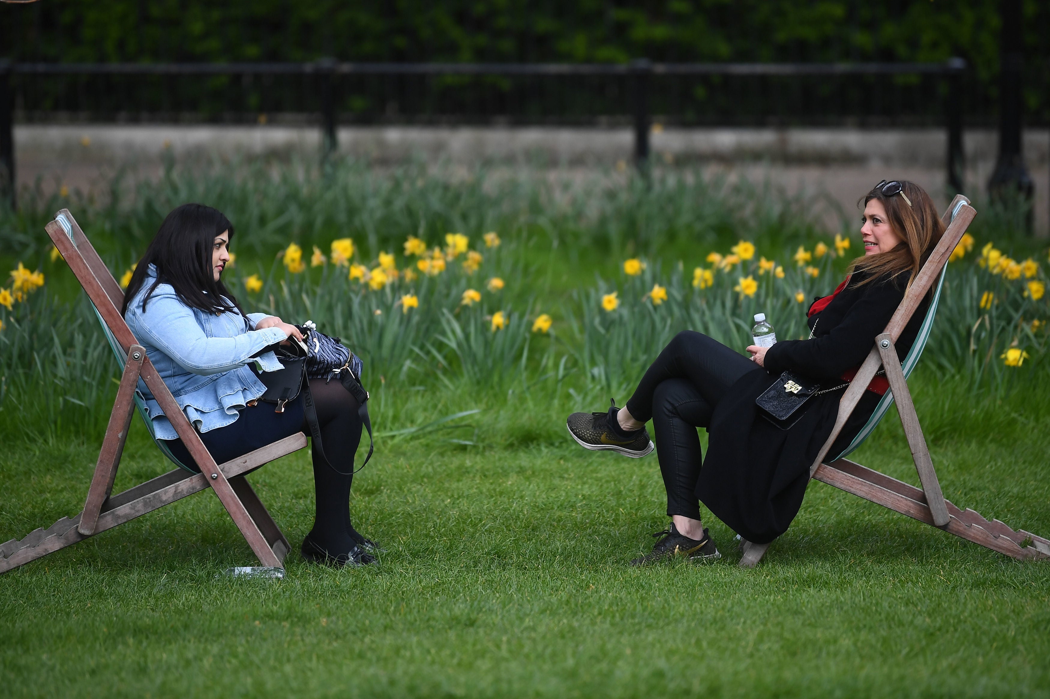 Two women sitting in deck chairs in Green Park, London, after Covid rules were relaxed this week
