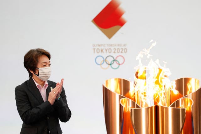 Tokyo 2020 President Seiko Hashimoto applauds next to the celebration cauldron