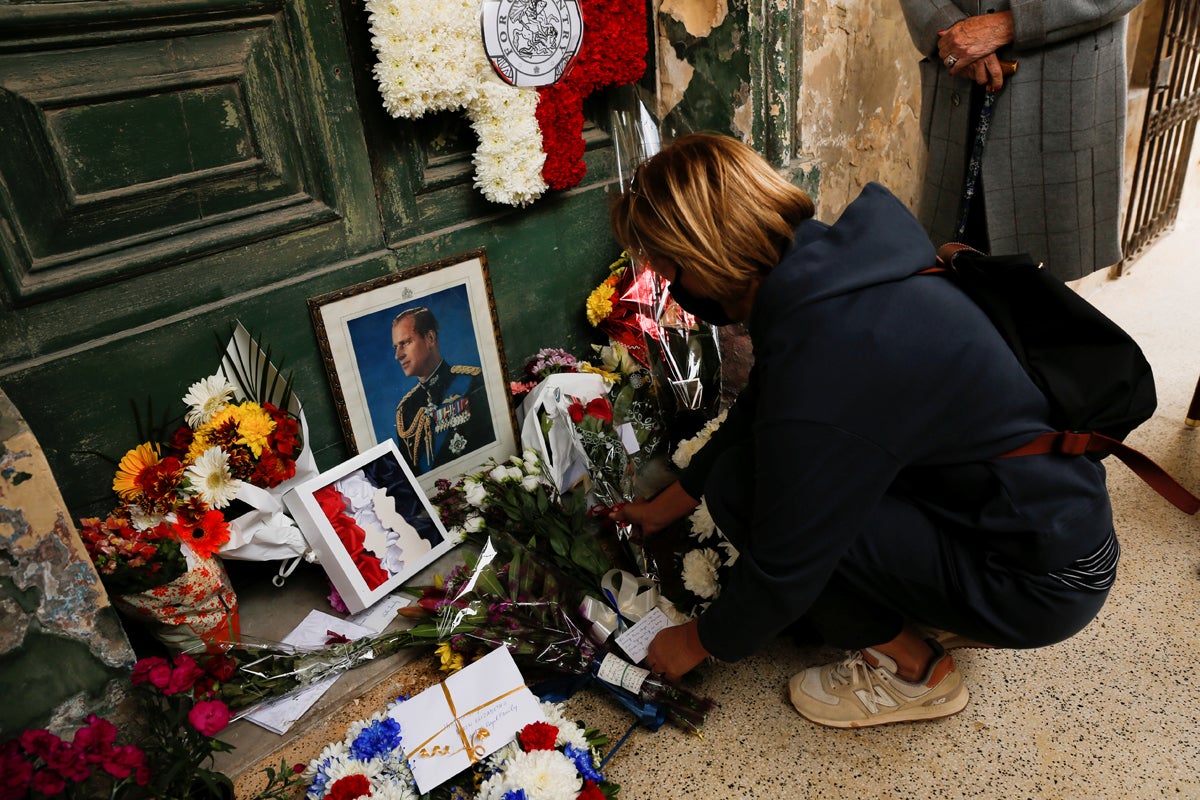 A woman lays flowers to honour Prince Philip before his funeral, outside Villa Guardamangia, a former residence of Britain's then-Princess Elizabeth and Prince Philip between 1949 and 1951, in Pieta, Malta