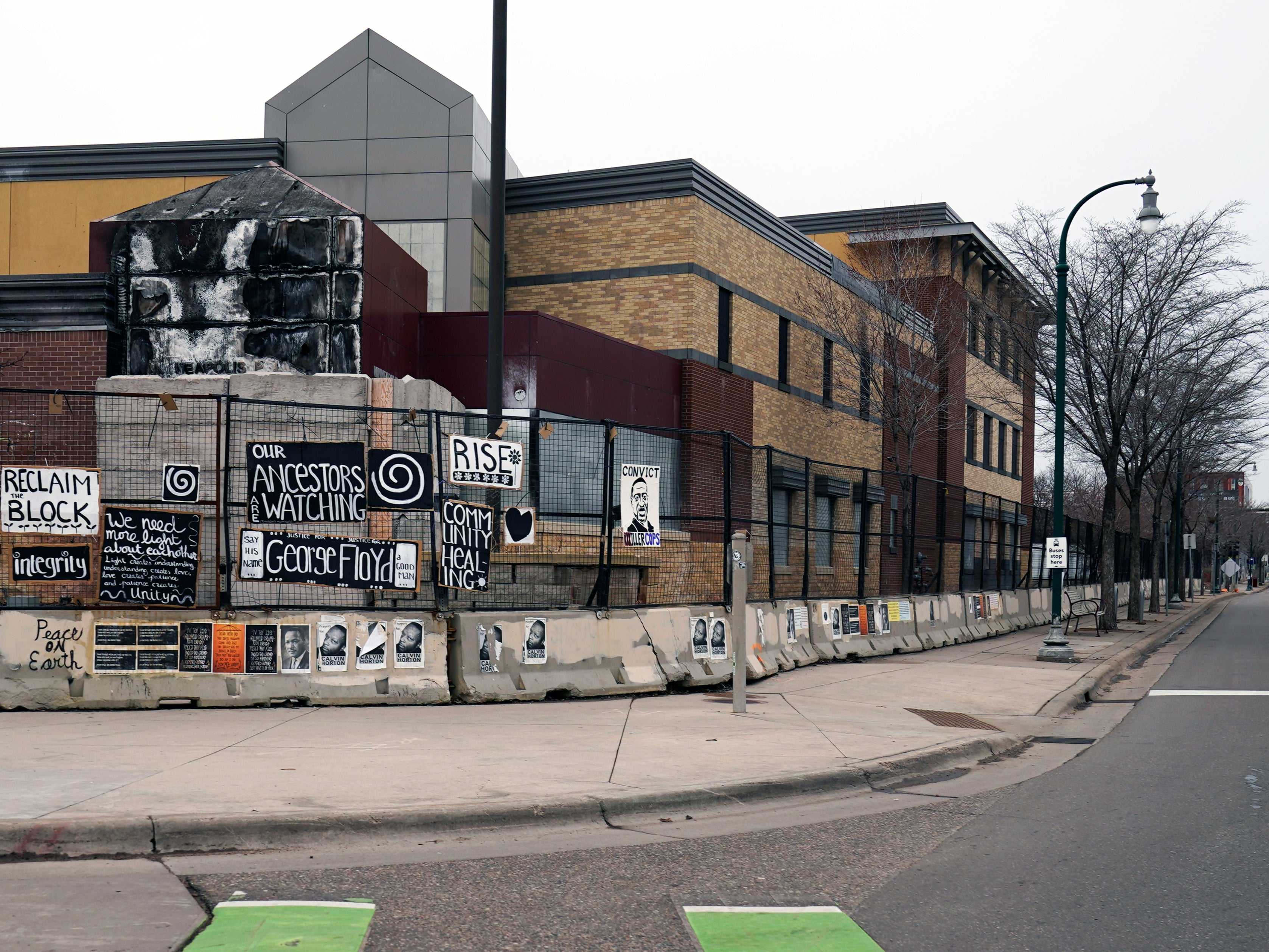 Signs hang on a fence amid the remains of the Minneapolis 3rd Precinct police station that was burned down by protesters 23 March, 2021