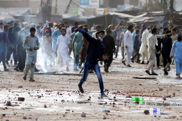 <p>An anti-French protester hurls stones towards police during a protest in Lahore, Pakistan</p>