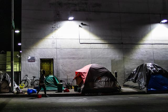 <p>A homeless man is seen among tents on the street of Skid Row during the Covid-19, Coronavirus pandemic in Los Angeles, California on 16 May 2020</p>
