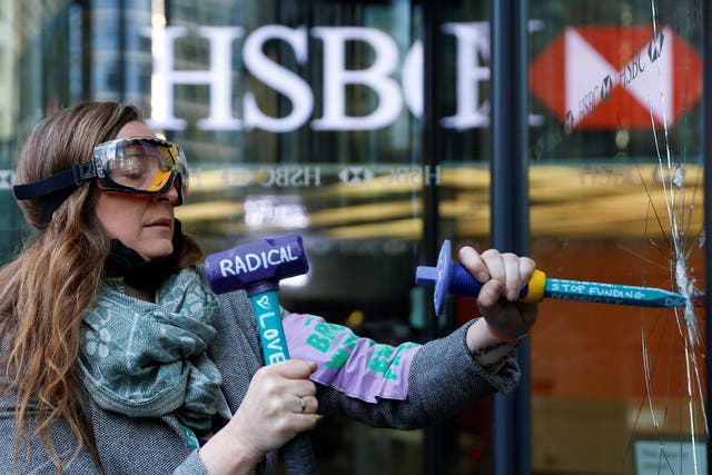 An activist from the Extinction Rebellion shatters a window at HSBC headquarters in Canary Wharf