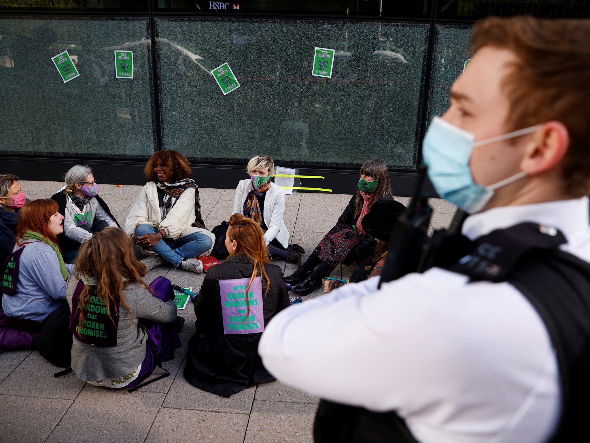 Activists sit down after smashing the windows as police attend the scene