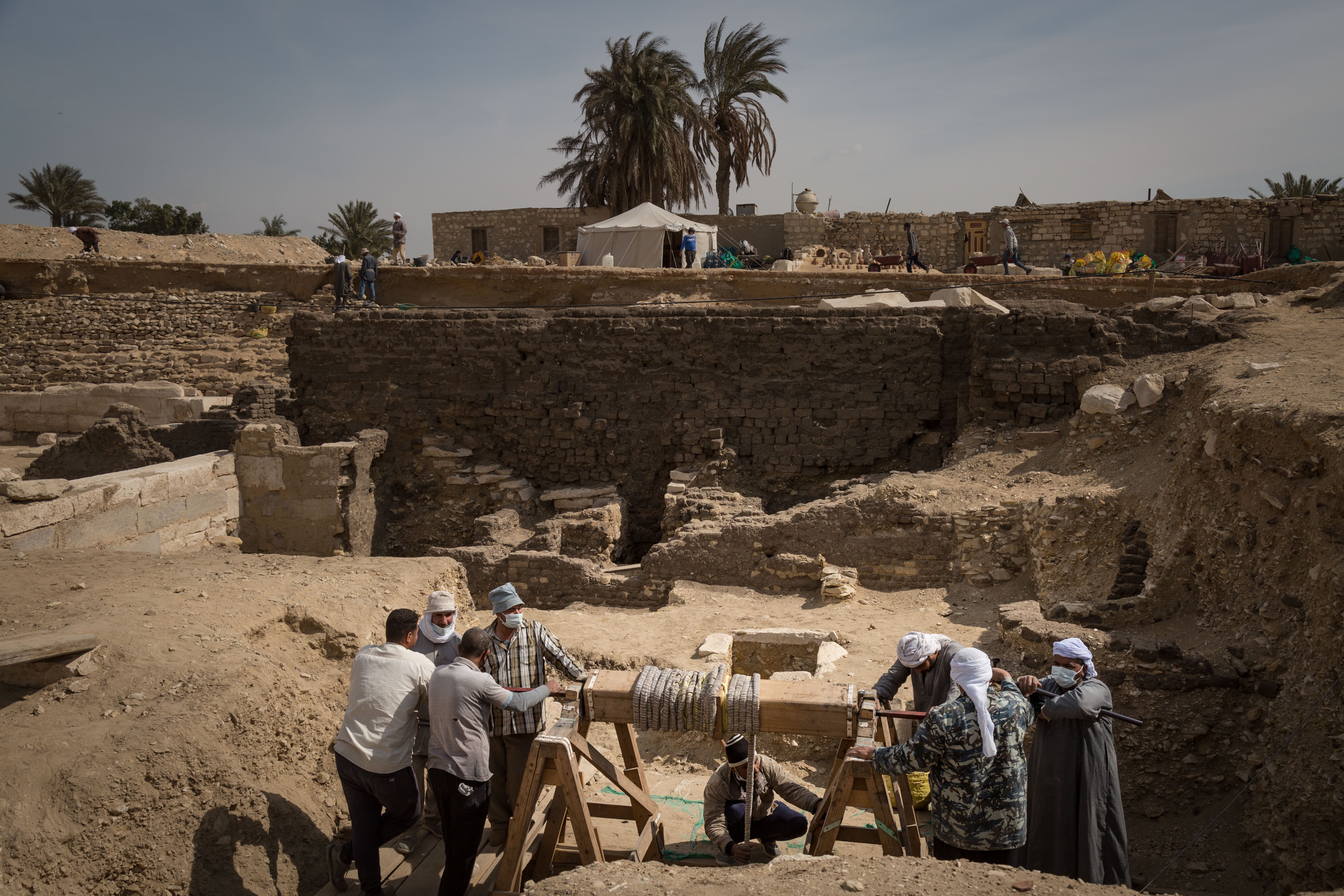 One of the archaeologists is winched out of a shaft using a pulley and basket