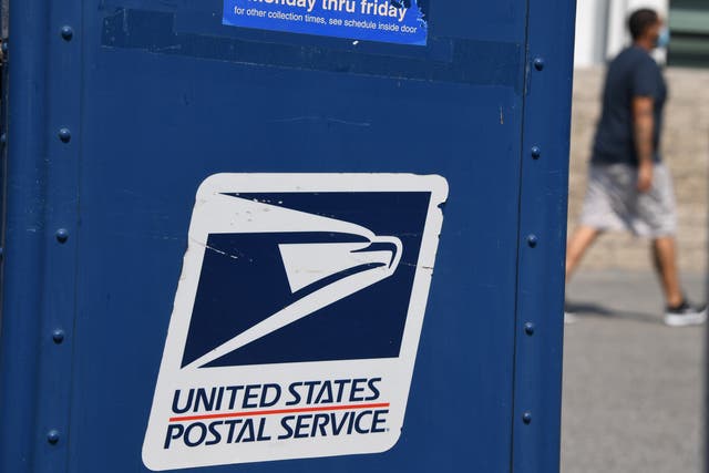 <p>A man walks past a mail box outside a post office in Los Angeles, California on 17 August 2020</p>