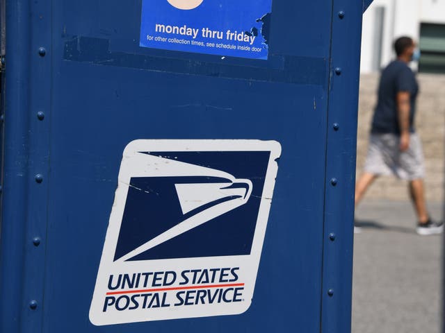 <p>A man walks past a mail box outside a post office in Los Angeles, California on 17 August 2020</p>