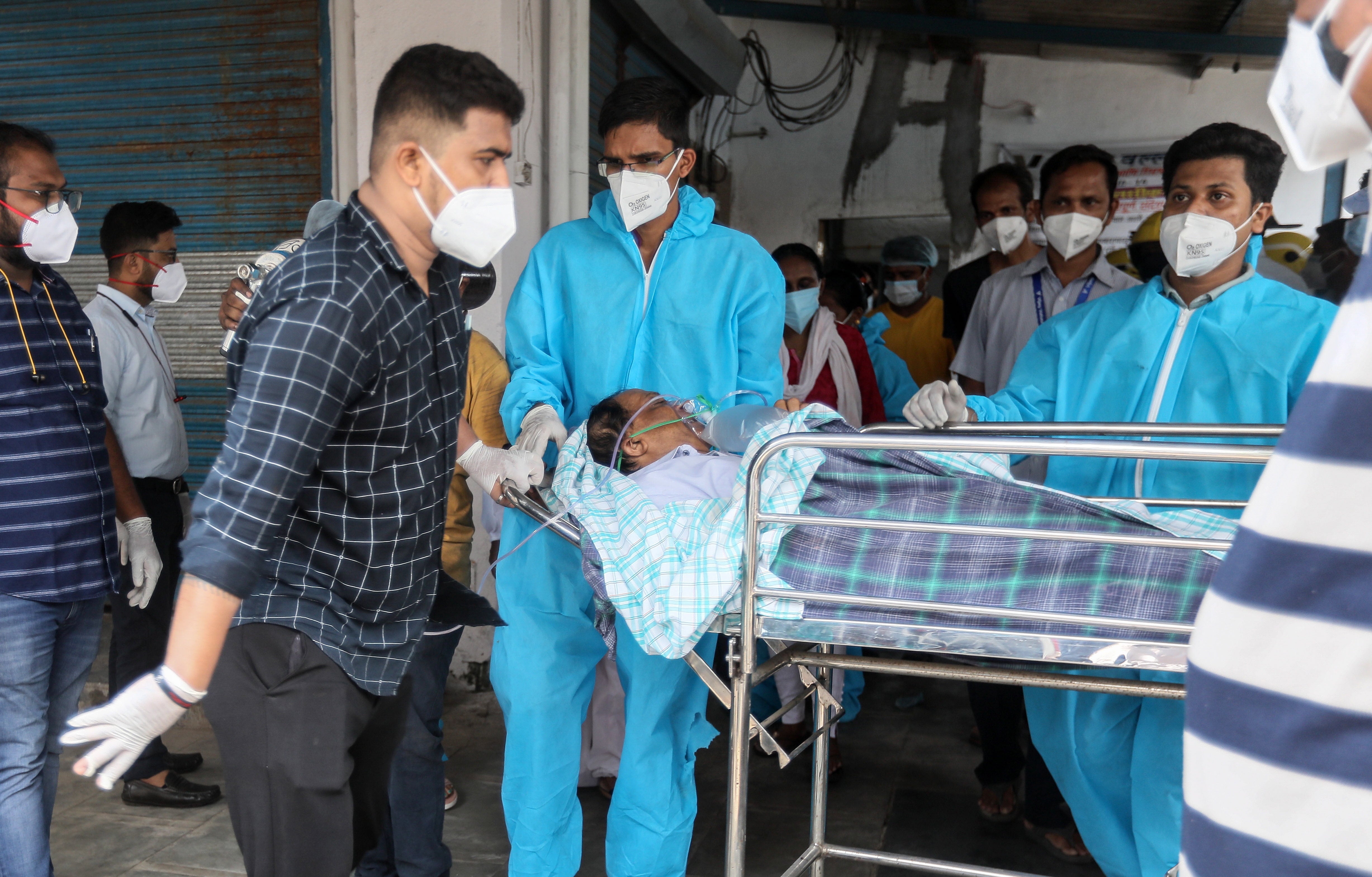 Health workers move a suspected Covid-19 patient outside the Vijay Vallabh hospital in the aftermath of a fire