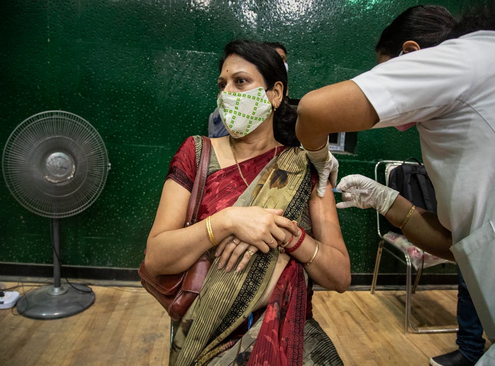 A woman receives the COVAXIN vaccine for COVID-19 at an indoor stadium in Gauhati, India