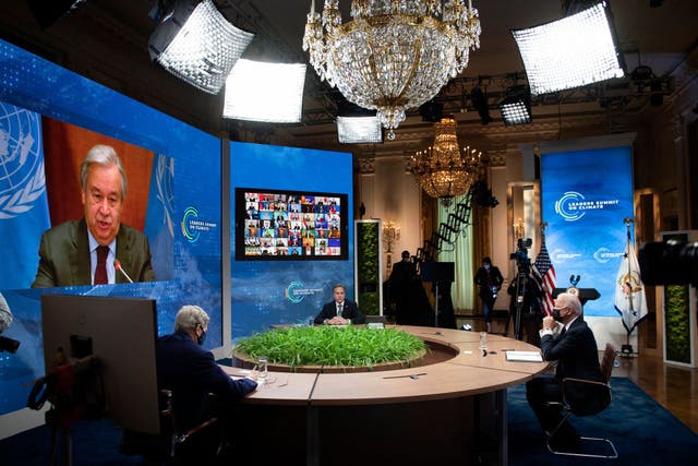 (From L-R) Climate envoy John Kerry, Secretary of State Antony Blinken, and President Biden listen as UN Secretary General Antonio Guterres speaks on screen during the climate summit from the East Room of the White House on 22 April