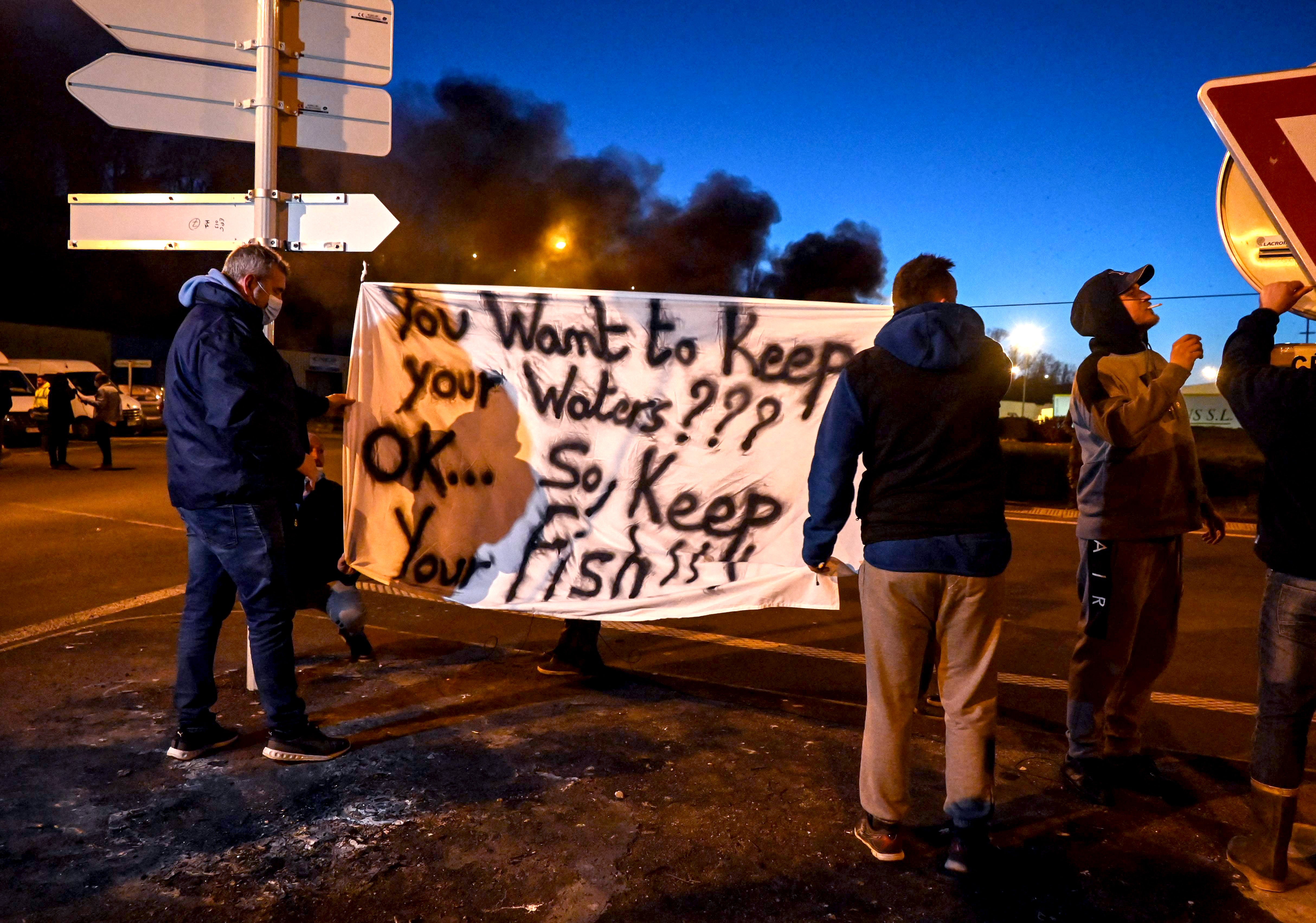 French fishermen in Boulogne-sur-Mer hold a banner as they block lorries carrying UK-landed fish