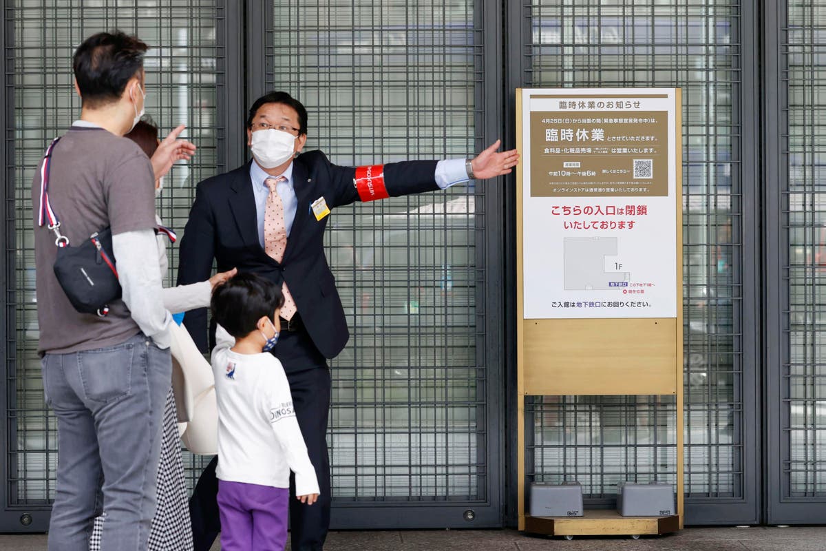 The Latest: Japan shuts stores, bars, theaters to slow surge