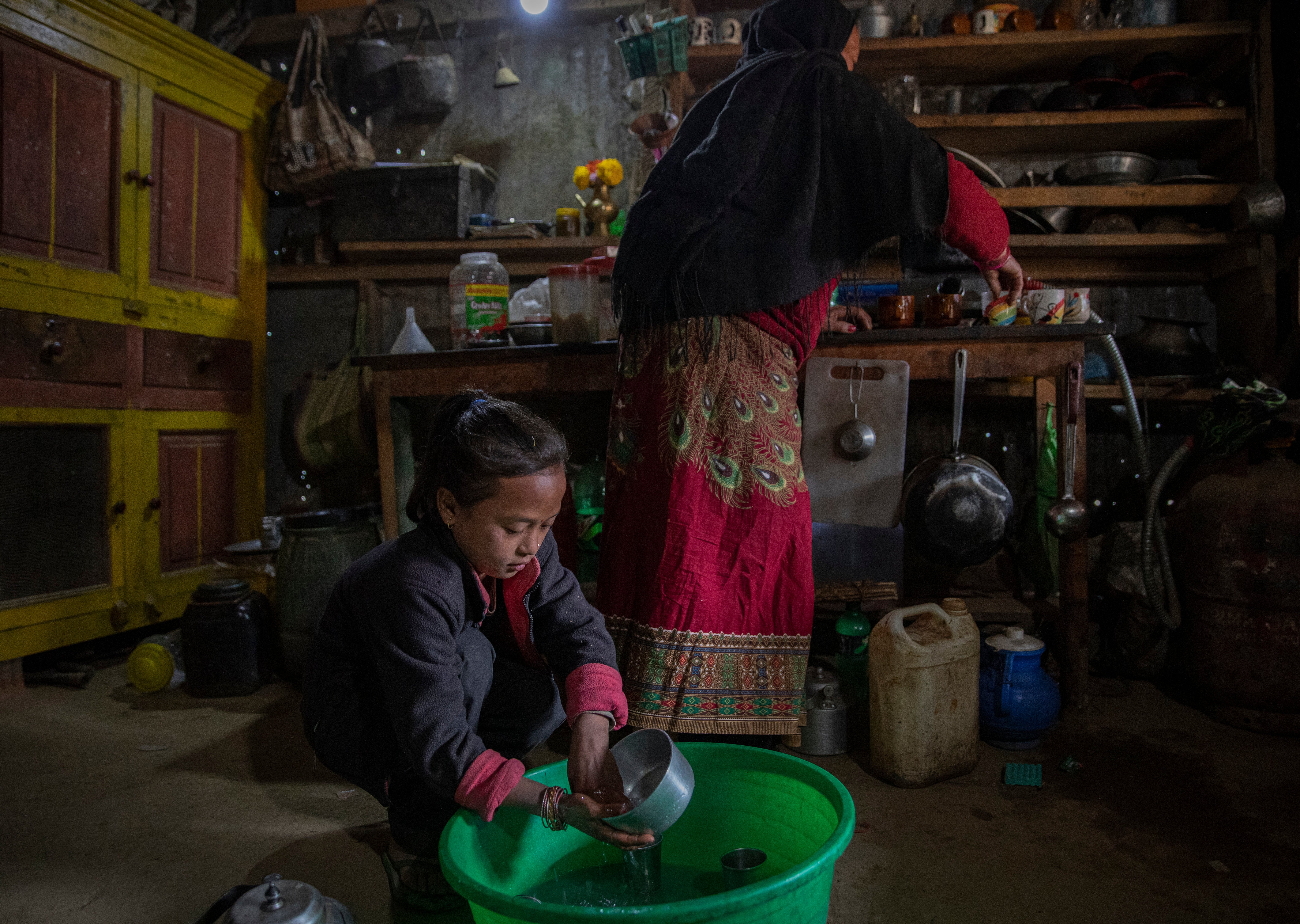 Chimini, 11, works alongside her grandmother cooking and serving noodles to the villagers in their kitchen shop. Her father has gone to Qatar to earn better money.