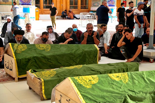 <p>Mourners pray at a funeral by the coffins of coronavirus patients that were killed in the hospital fire</p>