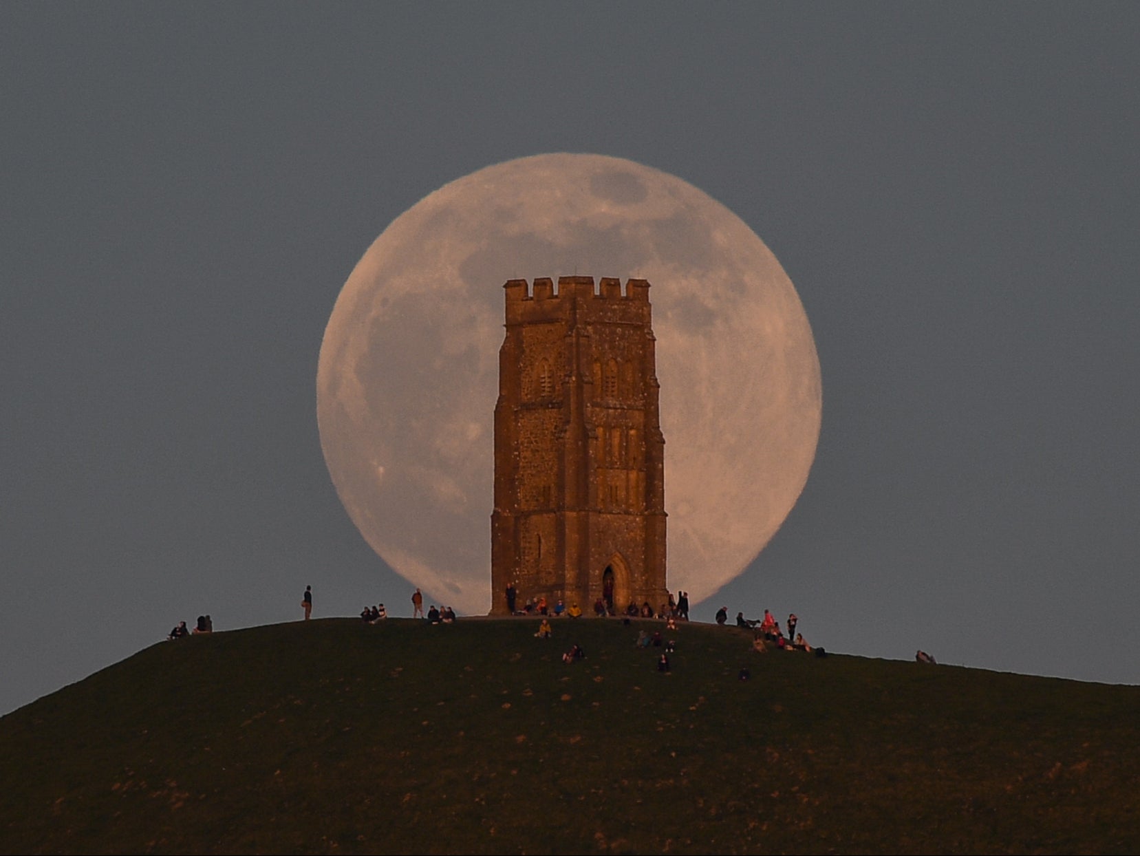 The full moon rises behind Glastonbury Tor on 26 April 2021 in Glastonbury, England