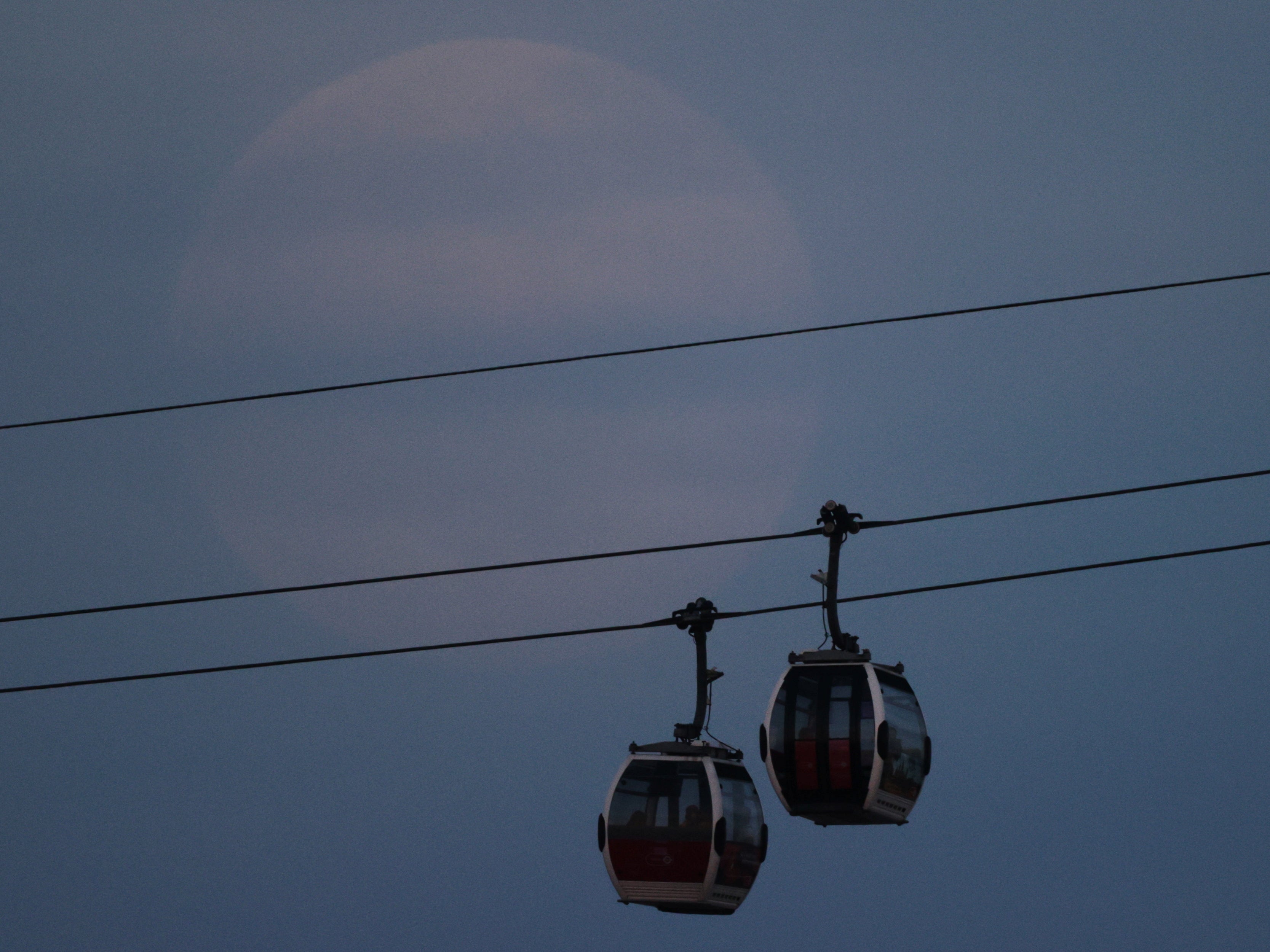 Passengers travel on the Emirates Air Line cable car as the full moon, also known as the Supermoon, rises in London