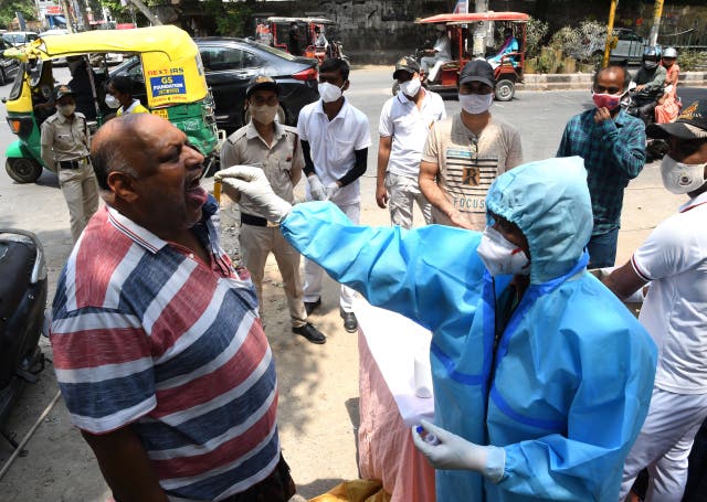 <p>A health worker takes a swab sample to test for Covid-19 at a roadside testing centre in Delhi</p>