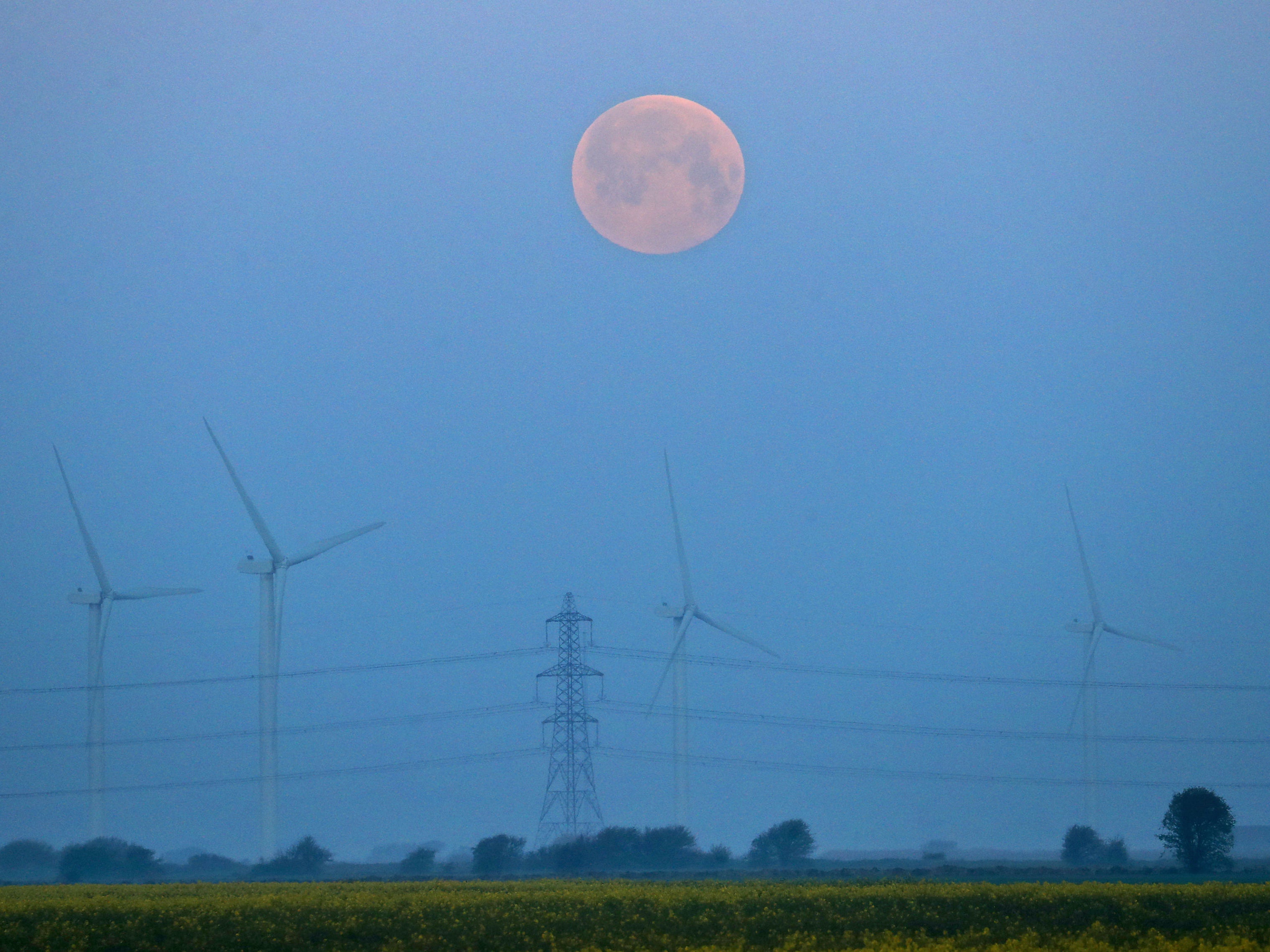 A full moon sets over Little Cheyne Court Wind Farm on the Romney Marsh in Kent, on Monday, during the frostiest April for over 60 years
