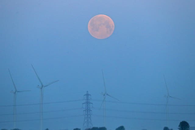 <p>A full moon sets over Little Cheyne Court Wind Farm on the Romney Marsh in Kent, on Monday, during the frostiest April for over 60 years</p>