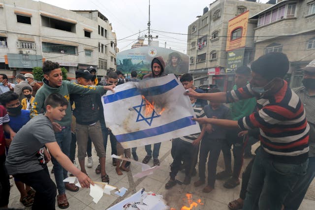 Palestinians burn a representation of an Israeli flag during an anti-Israel protest over tension in Jerusalem, in the southern Gaza Strip