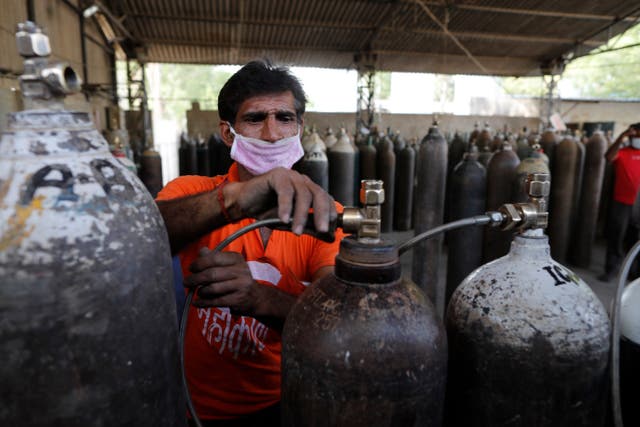 <p>A worker refills medical oxygen cylinders at a charging station on the outskirts of Prayagraj, India, on 23 April, 2021</p>