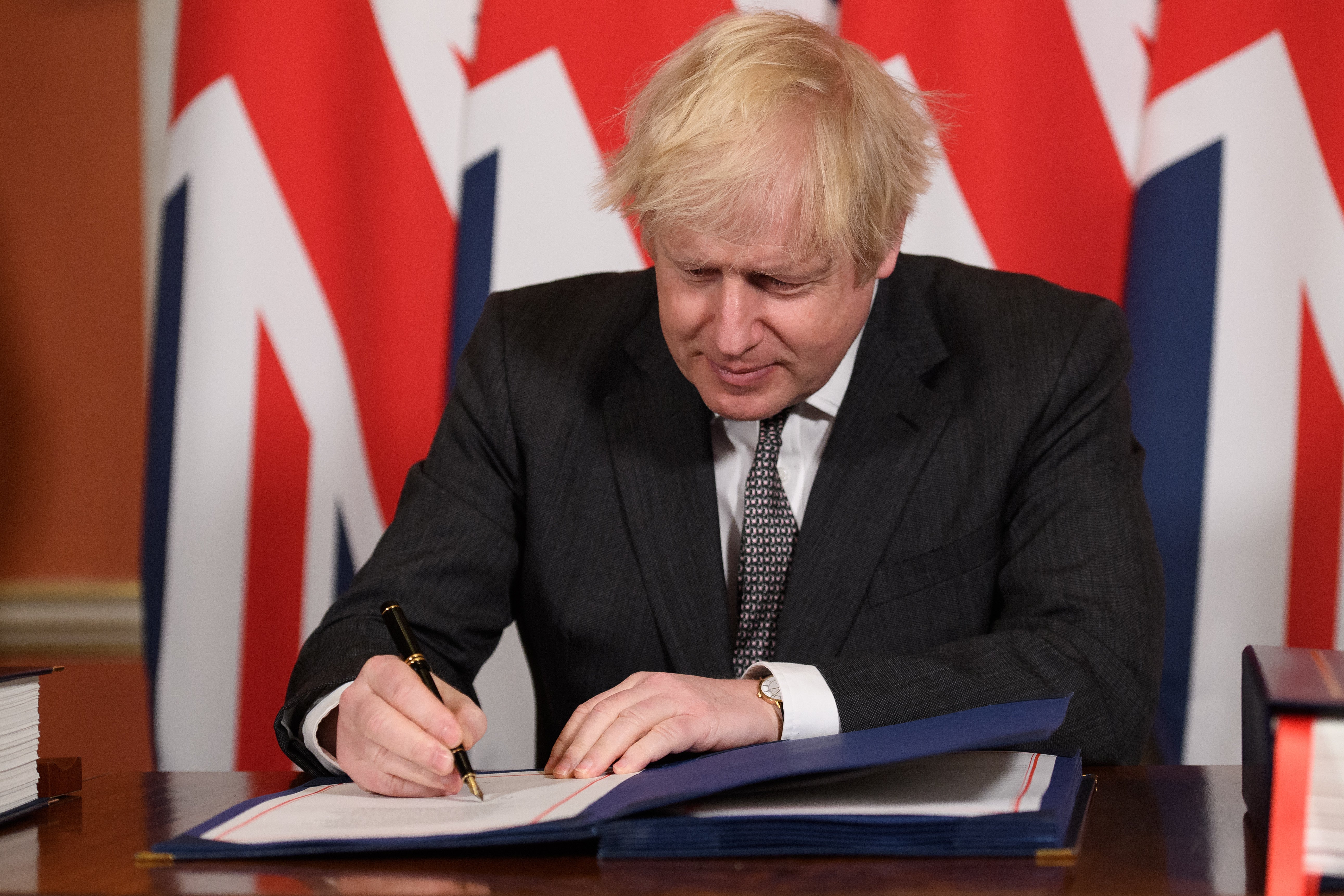 Boris Johnson signs a page of the Brexit trade deal with the EU in number 10 Downing Street on December 30, 2020