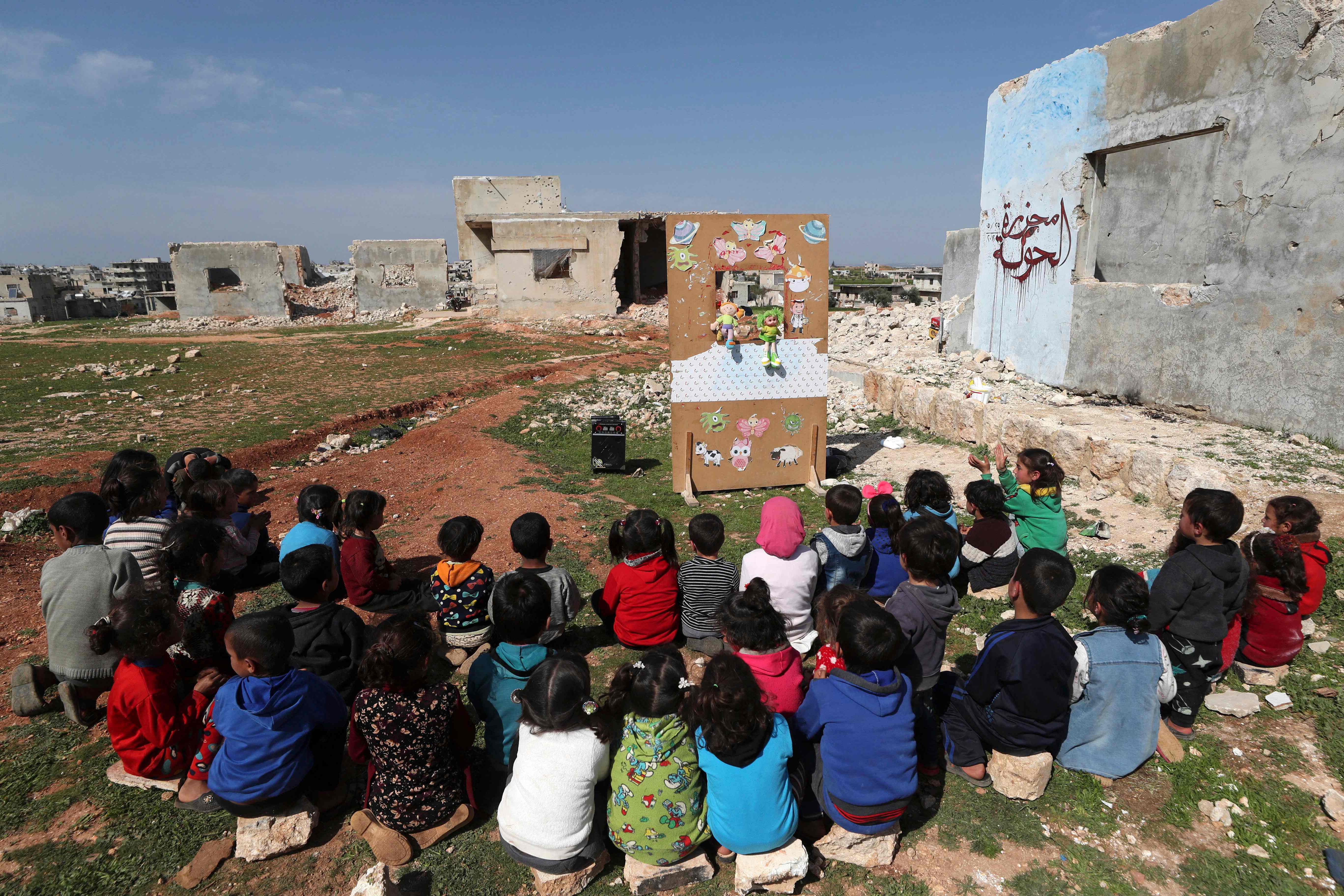 Syrian children watching a makeshift puppet show in the country’s northwestern Idlib province last month