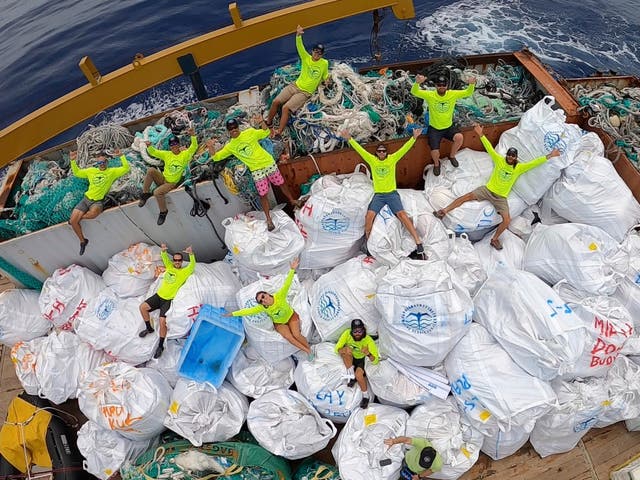 In this April 21, 2021 photo provided by Andy Carre, workers with the Papahanaumokuakea Marine Debris Project pose on top of fishing nets and plastics collected from the the beaches of the Northwestern Hawaiian Islands.