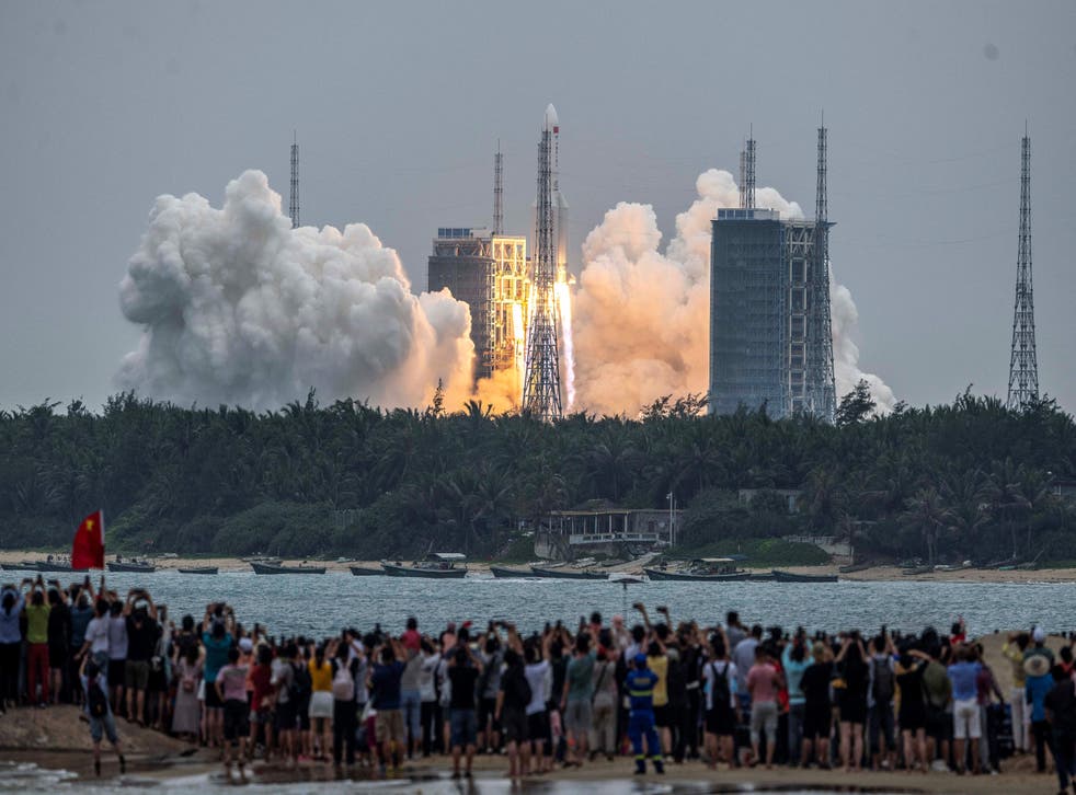 People watch a Long March 5B rocket, carrying China's Tianhe space station core module, as it lifts off from the Wenchang Space Launch Center in southern China's Hainan province