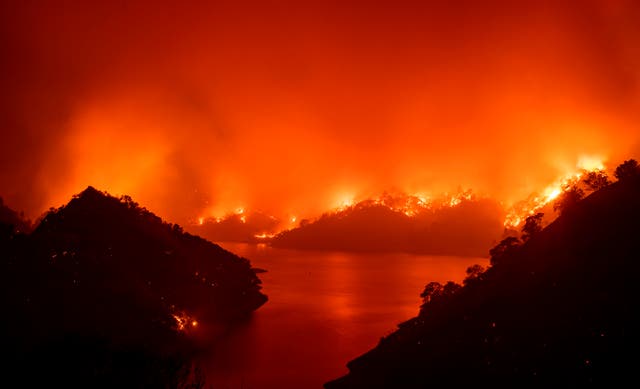 <p>Flames surround Lake Berryessa during the August 2020 wildfires.</p>