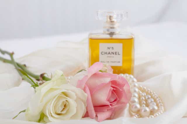 Chanel No5 bottle next to roses and pearls