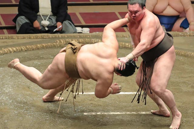 <p>Yokozuna-ranked sumo wrestler Hakuho (R) pushes down opponent Kagayaki in the ring in 2020</p>