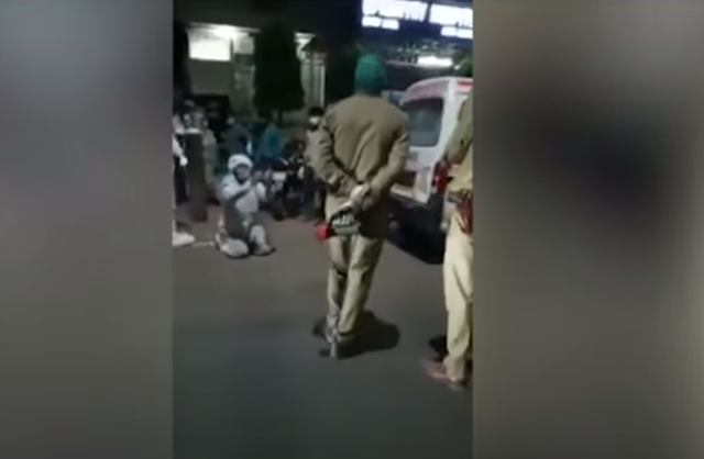 <p>A 22-year-old man in a PPE suit, on his knees, pleading before the Uttar Pradesh police not to take away his mother’s oxygen cylinder. Screengrab. </p>