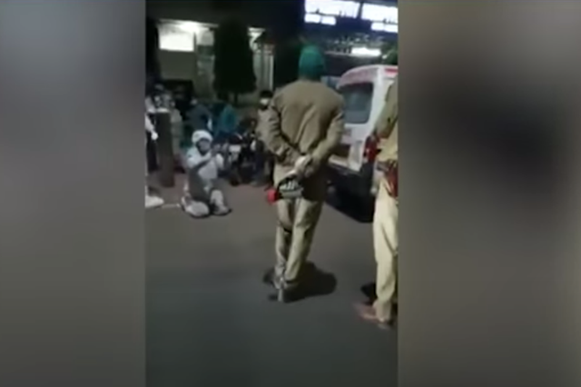 <p>A 22-year-old man in a PPE suit, on his knees, pleading before the Uttar Pradesh police not to take away his mother’s oxygen cylinder. Screengrab. </p>